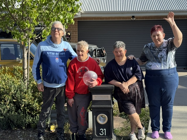 Four people smiling together outside a home