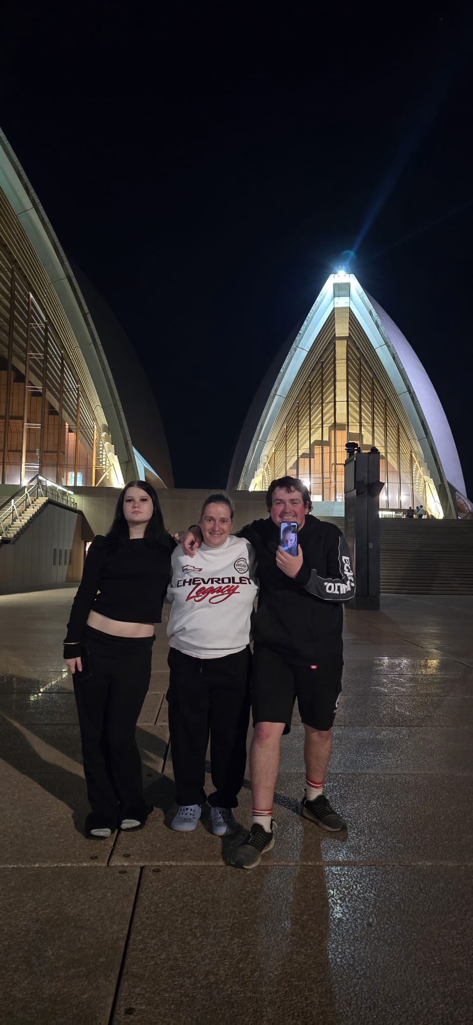 Three people together at the Sydney Opera House at night